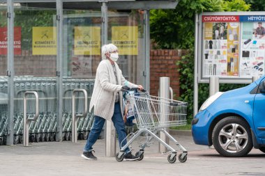 PECS - 27 Mayıs: 27 Mayıs 2020 tarihinde yaşlı kadın Pecs, Macaristan 'da alışverişe gider. Coronavirus salgını sırasında herkes maske takmak zorundadır.