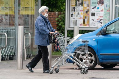 PECS - 27 Mayıs: 27 Mayıs 2020 tarihinde yaşlı kadın Pecs, Macaristan 'da alışverişe gider. Coronavirus salgını sırasında herkes maske takmak zorundadır.