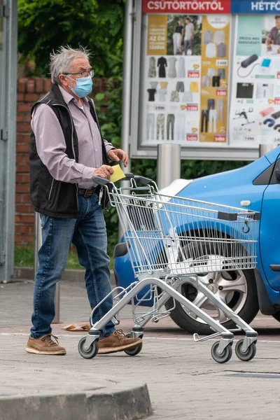 Yaşlı adam 27 Mayıs 2020 'de Macaristan' ın Pecs kentinde alışverişe çıkar. Coronavirus salgını sırasında herkes maske takmak zorundadır.