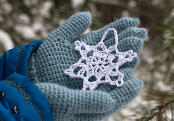 Snowflake knitted from yarn on hands in knitted gloves