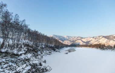 Katun nehirde buz kaplı güzel dağlar karlı zirveleri ile ve çam ormanı ile açık mavi gökyüzü arka plan