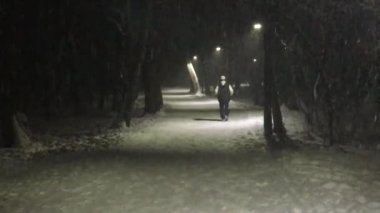 Koşu yağan kar altında ve sokak lambaları ışığında bir adam