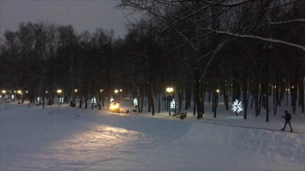 Liten Snøfjernende Traktor Med Frontlykter Slått Rengjør Gangstien Byparken Snøen – stockvideo