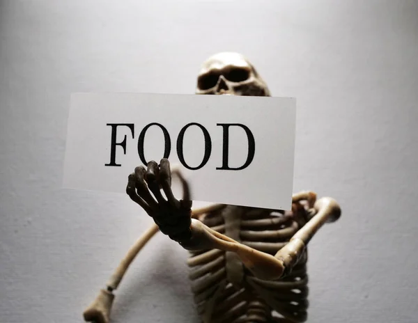 Σκελετός Που Κατέχει Μια Ετικέτα Τροφίμων Που Υποδηλώνει Έλλειψη Τροφής — Φωτογραφία Αρχείου
