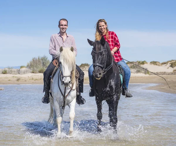 女と男がビーチで彼女の種馬に乗って — ストック写真