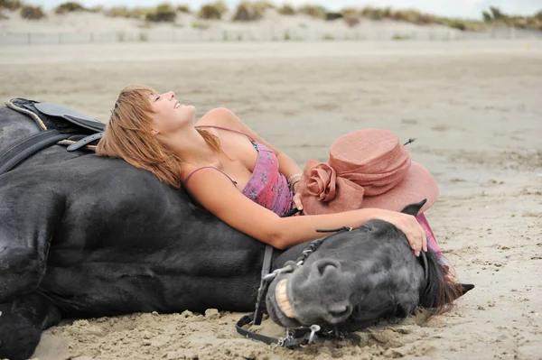 快乐的女人和她的种马躺在沙滩上 — 图库照片