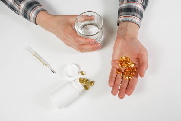 Man hand holds yellow medication capsules of omega 3
