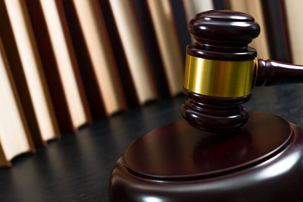 Судья молоток рядом с грудой книг
