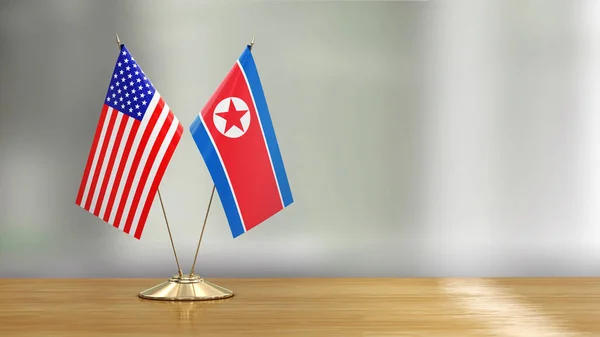 American and North Korean flag pair on a desk over defocused background