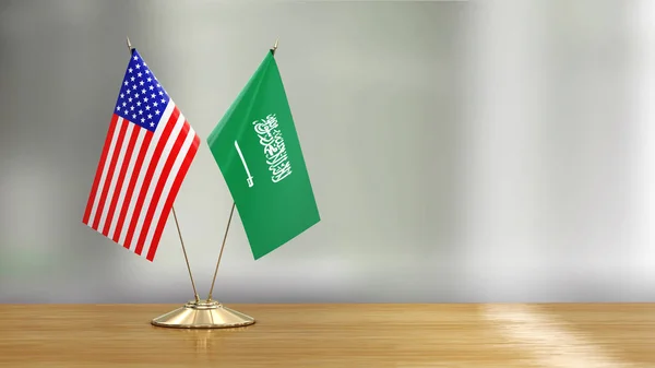 アメリカとサウジアラビアの旗のペアは デフォーカスの背景上の机の上 — ストック写真