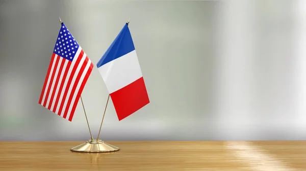 American and French flag pair on a desk over defocused background