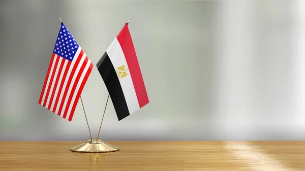 American and Egyptian flag pair on a desk over defocused background