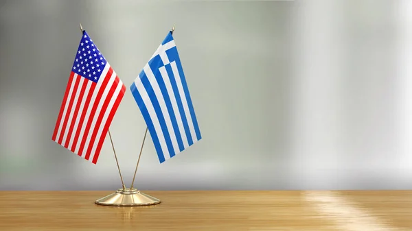 American and Greek flag pair on a desk over defocused background