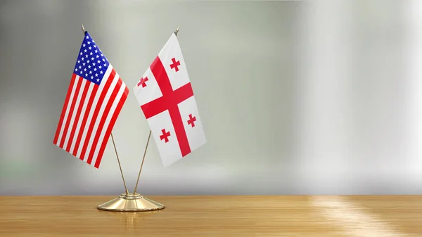 American and Georgian flag pair on a desk over defocused background