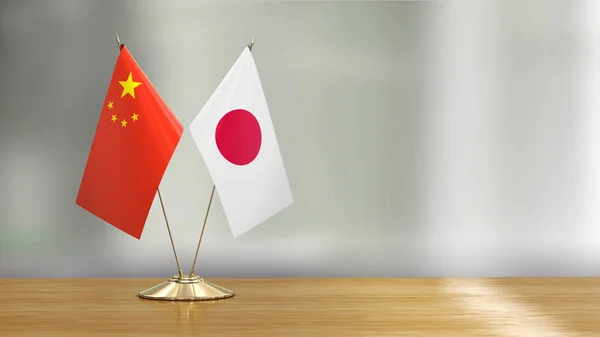 Chinese and Japanese flag pair on a desk over defocused background