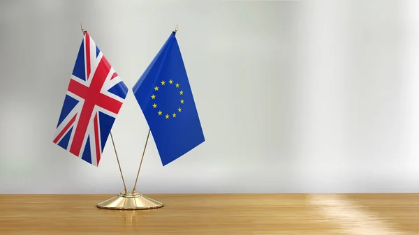 British and European Union flag pair on a desk over defocused background