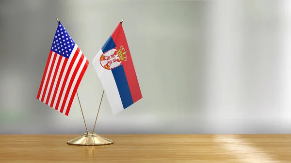 American and Serbian flag pair on a desk over defocused background