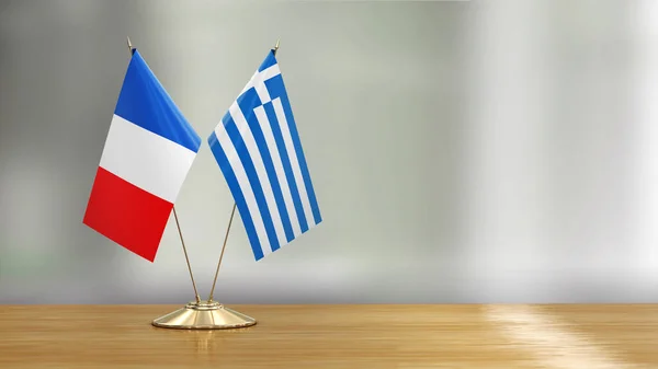 French and Greek flag pair on a desk over defocused background