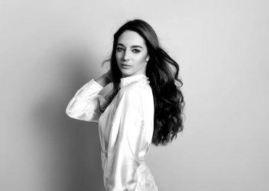 Uzun dalgalı ve sağlıklı saçlı güzel bir kadın. Elbise giymiş.