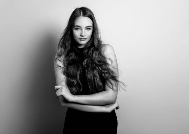 Uzun dalgalı ve sağlıklı saçlı güzel bir kadın. Elbise giymiş.