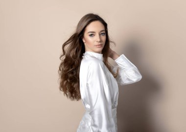 Uzun dalgalı ve sağlıklı saçlı güzel bir kadın. Elbise giymiş.