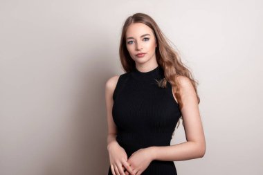 Uzun dalgalı ve sağlıklı saçlı güzel bir kadın. Elbise giymiş.