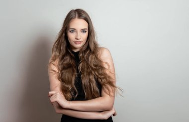 Uzun dalgalı ve sağlıklı saçlı güzel bir kadın. Elbise giymiş.