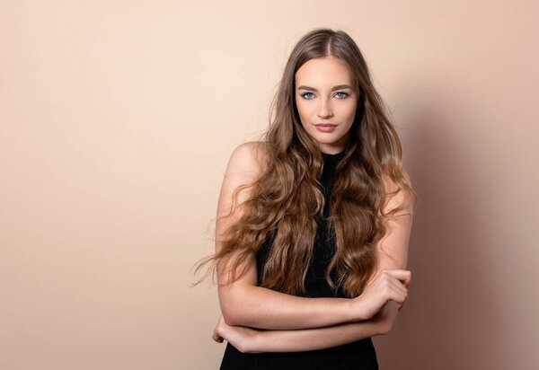 Красивая молодая женщина с длинными волнистыми и здоровыми волосами позирует в платье