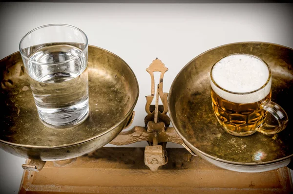 Beer and water on vintage scales, an alcoholism concept