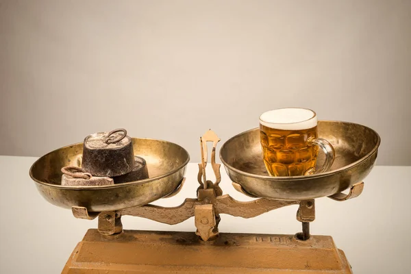 Beer and water on vintage scales, an alcoholism concept