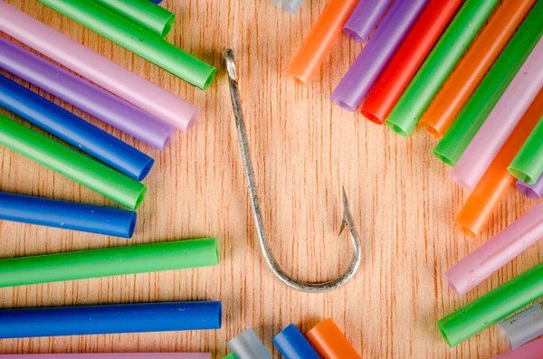 Fishing hook surrounded by drinking straws, a concept of the pollution of the oceans with plastic waste and its dangers for marine life.