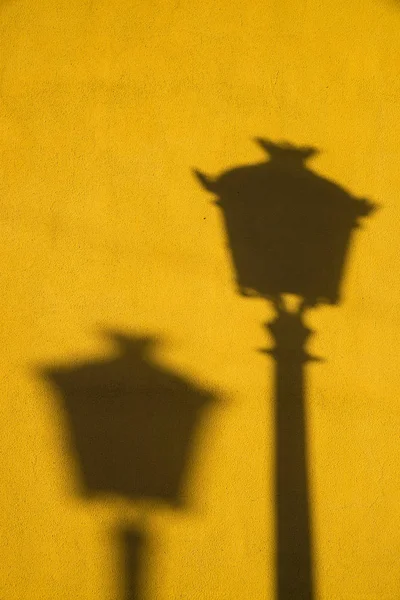 Long and strong winter light shadows on a yellow wall