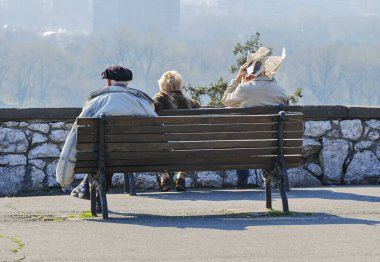 Yaşlı insanlar bankta oturur ve manzaranın tadını çıkarırlar.