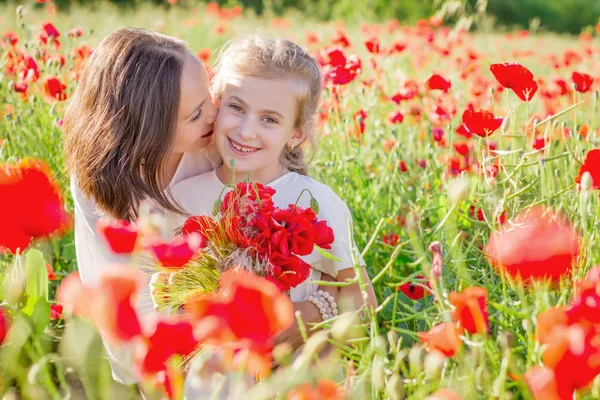 母亲黑发在白色礼服与女儿一起亲吻盛开的红色罂粟田 — 图库照片