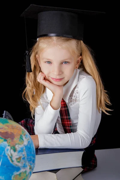 帽子とグローブ黒の背景 教育と学校のコンセプトに座っている女子高生 — ストック写真