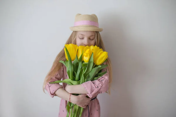 黄色のチューリップをかぐ十代の少女、花に焦点を当てる — ストック写真