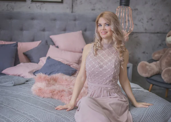 Glamour woman in dress sitting in gray and pink bedroom