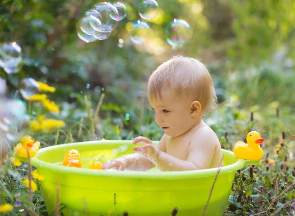 Menino na bacia tomando um banho com bolhas e pato — Fotografia de Stock