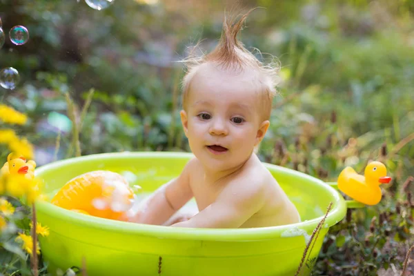 Kleinkind im Becken badet mit Blasen und Entenspielzeug — Stockfoto