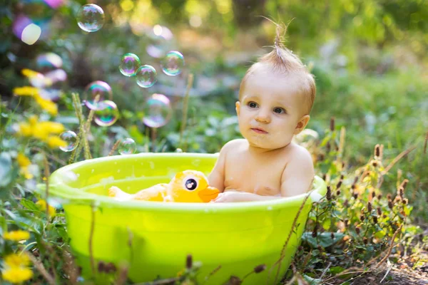 Kleinkind im Becken badet mit Blasen und Entenspielzeug — Stockfoto