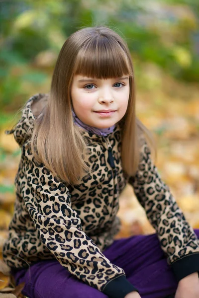 漂亮的女孩在一个有斑点的夹克坐在地面上对 b — 图库照片