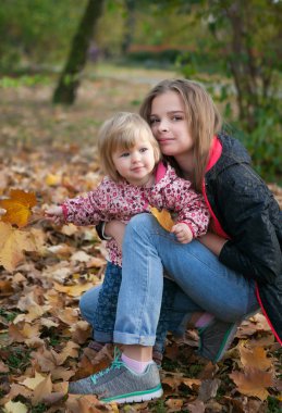 iki küçük kız kardeş büyük ve sonbahar parkta küçük sarılma