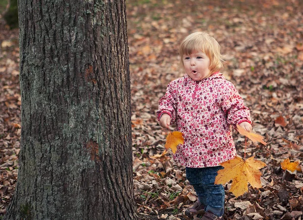 Little cute cheerful girl 1 year old in autumn park with yellow — Stock Photo, Image