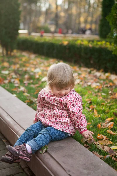Pequeña linda chica alegre 1 año de edad en el parque de otoño con amarillo — Foto de Stock