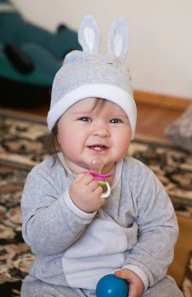 Маленька дівчинка в сірому костюмі і капелюсі з вухами кролика посміхається — стокове фото