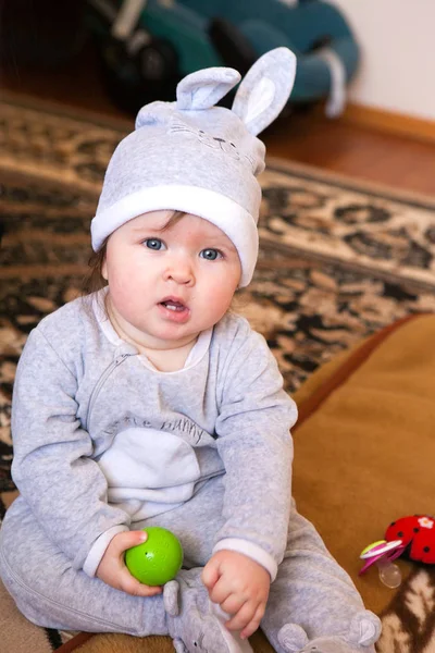 Маленька дівчинка в сірому костюмі і капелюсі з вухами кролика посміхається — стокове фото