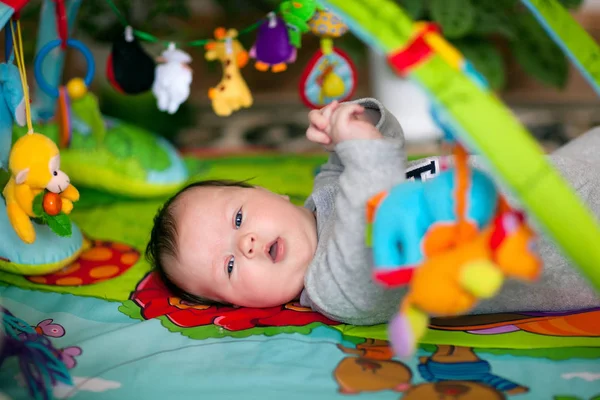 6 개월 된 어린 소녀는 멀티 컬러 개발 양탄자에 누워 — 스톡 사진