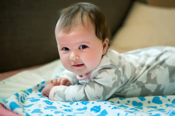 Niña pequeña 6 meses acostada sobre su estómago, sosteniendo su cabeza en un —  Fotos de Stock