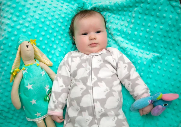 6 개월 된 어린 소녀는 딸랑이와 민트 밝은 양탄자에 누워 — 스톡 사진