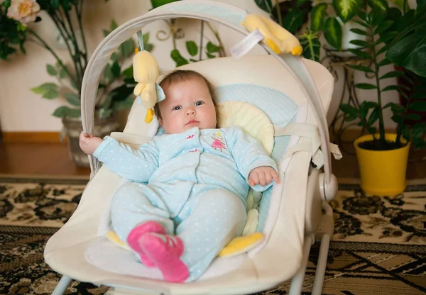 Baby in a blue jumpsuit is lying on a deck chair smiling — Stock Photo, Image